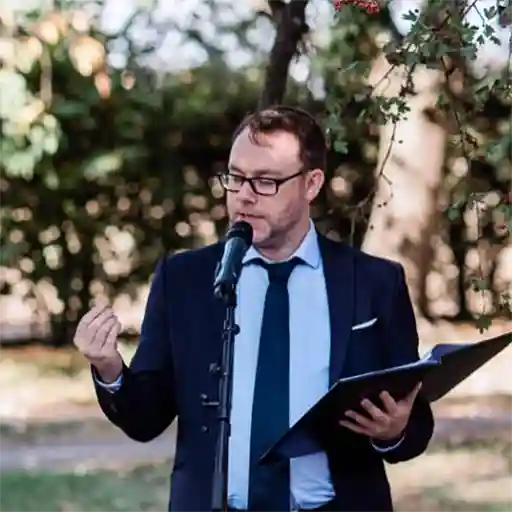 Rhetorik-Trainer Marco Herr im Einsatz. Zeit Marco vor Mikrofon mit Skript in der Hand bei Moderation oder Vortrag.